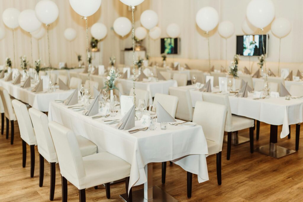 Stylish wedding reception setup in a restaurant with balloons and white theme decor.