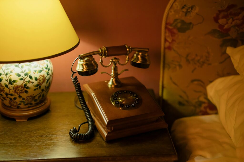 Classic hotel room decor featuring an antique telephone and floral lamp.