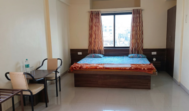 Spacious premium non AC room with double bed and modern ceiling lights at Shivrudra Hotel Lohegaon